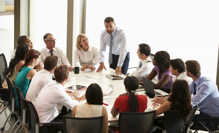 Businessman Addressing Meeting Around Boardroom Table